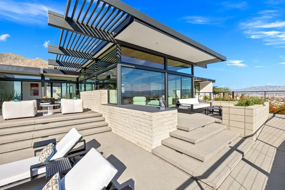 A louvred pergola shading an outdoor kitchen and lounge.
